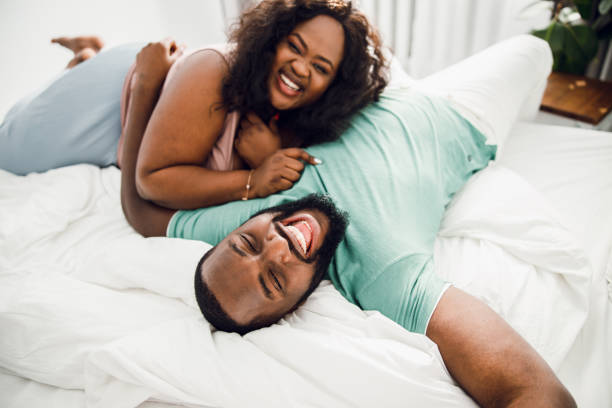 Excited man lying on the bed and laughing with his beloved woman